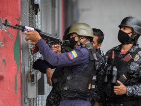 Members of the Bolivarian National Police aim at possible targets after clashes with alleged members of a criminal gang at the Cota 905 neighborhood in Caracas on July 9, 2021.