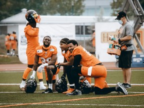 Receivers Shaq Johnson, Lemar Durant and Bryan Burnham take a knee and catch up during a break at B.C. Lions training camp in Kamloops on Tuesday.