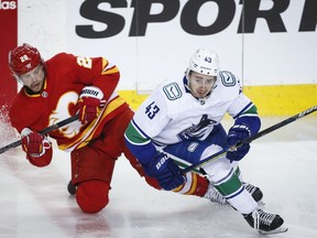 Vancouver Canucks' Quinn Hughes, right, avoids a check from the Calgary Flames' Elias Lindholm during NHL action in Calgary on May 19.