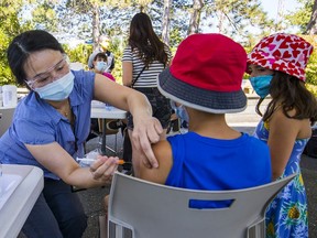 Ada Zeng of Coastal Health gives a COVID-19 vaccination to Joseph, 13. After taking a spin on the AtmosFear and snacking on hotdogs and mini donuts, people visiting Playland this weekend were invited to stop by the one-immunization clinic.