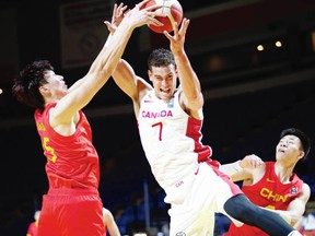 Canada's Dwight Powell goes for a rebound over China's Qi Zhou, left, and Zhenlin Zhang in FIBA Olympic Qualifying Tournament action at Save-on-Foods Memorial Centre.