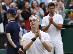 Canada’s Denis Shapovalov acknowledges the fans after losing his Wimbledon men’s semifinal match to Novak Djokovic of Serbia (in the background) on July 9, 2021 in London.