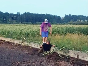 Sean Ferguson struggles in deep liquid manure to rescue a fawn while Dayton Nixon is there to help pull it out.