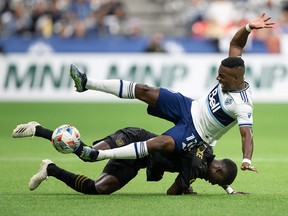 Vancouver Whitecaps' Cristian Dajome, top, and Los Angeles FC's Mamadou Fall collide during the first half at B.C. Place Stadium in Vancouver on Saturday, Aug. 21, 2021.