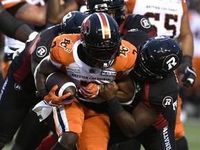 Ottawa Redblacks defensive lineman Praise Martin-Oguike grabs the arm of B.C. Lions running back Shaquille Cooper as he runs during first-half CFL football action in Ottawa on Saturday.