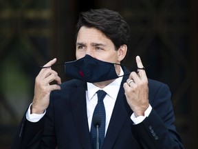 Prime Minister Justin Trudeau removes his mask as he prepares to speak at a news conference at Rideau Hall after meeting with Governor General Mary Simon to ask her to dissolve Parliament, triggering an election.