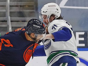 Rogers-sponsored — the helmets, at least — Darnell Nurse (left) of the Edmonton Oilers and Vancouver Canuck Zack MacEwen trade shots last season in Edmonton. Those type of helmet ads will move onto the players’ sweaters, starting in the 2022-23 NHL season.