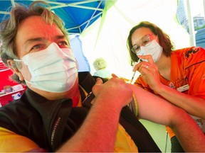 Ray Frison gets his vaccine shot from nurse Stephanie McLeod  and a free pass to a game, prior to the CFL game to start between BC Lions and Edmonton Elks at BC Place in Vancouver, BC, August 19, 2021.