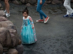A young girl in her princess outfit reacts to the sound of a dog in the 'Alice in Wonderland Maze' atraction on opening day at the Shanghai Disney Resort in Shanghai on June 16, 2016.