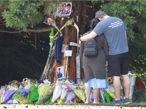 A couple stop to observe a roadside memorial in Surrey on Monday where three teenagers were killed in a single vehicle car crash this past weekend. The three young men killed were Parker Magnuson, Ronin Sharma and Caleb Reimer, all of whom recently played with the Delta Hockey Academy.