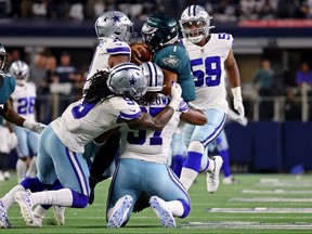 Eagles quarterback Jalen Hurts (1) is tackled by Dallas Cowboys linebacker Micah Parsons (top) and middle linebacker Jaylon Smith (left) and defensive tackle Osa Odighizuwa (bottom) in Week 3 actions The Eagles play the Chiefs this week.