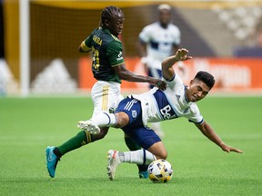 Portland Timbers' Diego Chara, left, and Vancouver Whitecaps' Michael Baldisimo vie for the ball during the first half of an MLS soccer game in Vancouver, on Friday, Sept. 10, 2021.