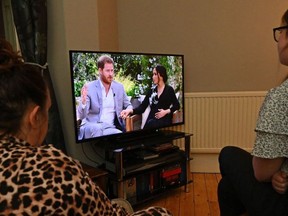 A family gather around the television in Liverpool, north west England to watch Prince Harry and his wife Meghan's explosive tell-all interview on CBS with Oprah Winfrey, on March 8, 2021, as national television in Britain shows the interview a day later then in the US.