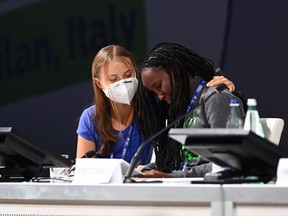 Swedish climate activist Greta Thunberg (L) comforts Ugandan climate activist Vanessa Nakate as Nakate reacts after delivering a speech during the opening plenary session of the Youth4Climate event on September 28, 2021 in Milan.