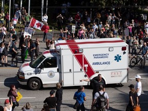 An ambulance passes through a crowd of people protesting COVID-19 vaccine passports and mandatory vaccinations for health-care workers in Vancouver earlier this month.