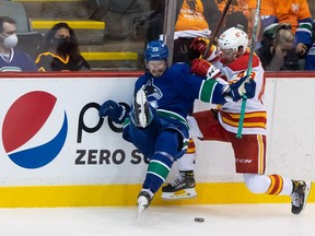 Canucks defenceman Oliver Ekman-Larsson (left) and Flames forward Luke Philp collide along the boards on Monday in Abbotsford. ‘It’s nice to see how fast he’s playing, moving the puck so well and how physical he is. He looks really engaged and looks like the Oliver I know,’ teammate Conor Garland — who came to the Canucks with Ekman-Larsson from Arizona — says of his fellow Canuck.