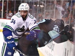 Seattle Kraken defenceman Carson Soucy (28) is hit into the glass by the Vancouver Canucks' Phillip Di Giuseppe (34) in the second period during a preseason game in 2021. Di Giuseppe has been added to the Canucks roster for an upcoming road trip.