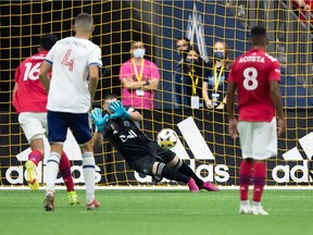 Vancouver Whitecaps' Brian White, front right, scores against FC Dallas goalkeeper Jimmy Maurer, back, as Justin Che defends during the first half of an MLS soccer game in Vancouver, on Saturday, September 25, 2021.