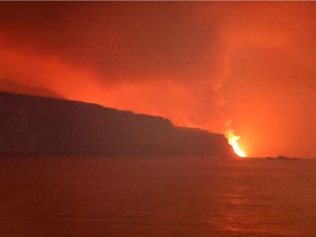 Lava flows into the sea as smoke rises following the eruption of a volcano, in the Port of Tazacorte, on the Canary Island of La Palma, Spain, September 28, 2021.