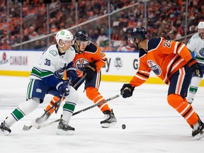 Jesse Puljujarvi (13) and Darnell Nurse (25) of the Edmonton Oilers battle Alex Chiasson (39) of the Vancouver Canucks at Rogers Place on Oct. 13 in Edmonton.