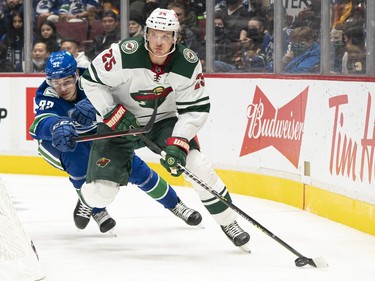 VANCOUVER, BC - OCTOBER 26: Jonas Brodin #25 of the Minnesota Wild skates the puck ahead of Vasily Podkolzin #92 of the Vancouver Canucks during the first period of NHL action on October, 26, 2021 at Rogers Arena in Vancouver, British Columbia, Canada.