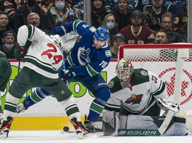 VANCOUVER, BC - OCTOBER 26: Tanner Pearson #70 of the Vancouver Canucks and Matt Dumba #24 of the Minnesota Wild battle for control of the puck  in front of goalie Cam Talbot #33 of the Wild during the first period of NHL action on October, 26, 2021 at Rogers Arena in Vancouver, British Columbia, Canada.