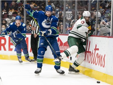VANCOUVER, BC - OCTOBER 26: Oliver Ekman-Larsson #23 of the Vancouver Canucks checks Marcus Foligno #17 of the Minnesota Wild into the end boards during the first period of NHL action on October, 26, 2021 at Rogers Arena in Vancouver, British Columbia, Canada.