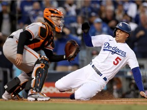 Corey Seager #5 of the Los Angeles Dodgers scores against Buster Posey #28 of the San Francisco Giants on a double by Trea Turner #6 during the first inning in game 4 of the National League Division Series at Dodger Stadium on October 12, 2021 in Los Angeles, California.