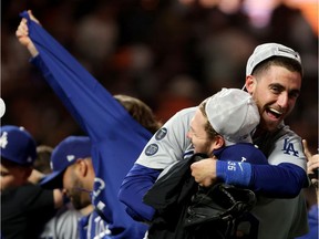 Gavin Lux #9 holds up Cody Bellinger #35 of the Los Angeles Dodgers as they celebrate their 2-1 win against the San Francisco Giants in game 5 of the National League Division Series at Oracle Park on October 14, 2021 in San Francisco, California.