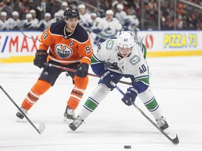 Vancouver Canucks' Elias Pettersson (40) is hooked by Edmonton Oilers' Ryan Nugent-Hopkins (93) during first period in preseason action in Edmonton on Thursday, Oct. 7, 2021.