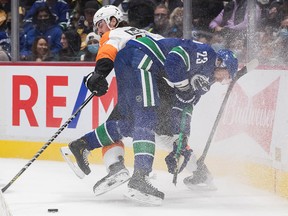 Vancouver Canucks' Oliver Ekman-Larsson (front), has his stick break as he's checked by Philadelphia Flyers' Zack MacEwen in the first period on Thursday, Oct. 28, 2021.