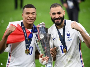 France's forward Kylian Mbappe (L) and France's forward Karim Benzema (R) celebrate with the trophy at the end of the Nations League final football match between Spain and France at San Siro stadium in Milan, on October 10, 2021.