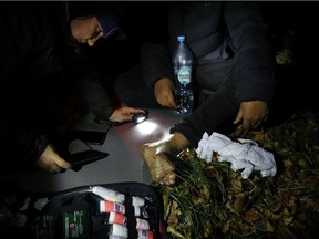 Piotr Bystrianin of the Ocalenie foundation covers the wound of the migrant after he crossed Belarusian-Polish border in the woods near Sokolka, Poland October 11, 2021.