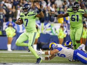 Seattle Seahawks quarterback Geno Smith (7) scrambles beyond the grasp of Los Angeles Rams defensive lineman Mike Hoecht (96) during the fourth quarter at Lumen Field.