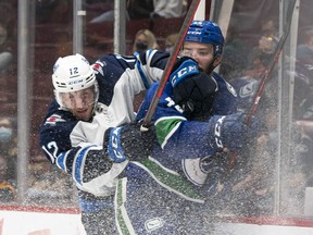 Vancouver Canucks' Kyle Burroughs (right) is checked into the end board by Winnipeg Jets' Jansen Harkins during third period NHL preseason hockey action in Vancouver, Sunday, Oct. 3, 2021.