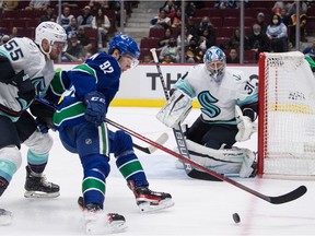 Seattle Kraken's Jeremy Lauzon (55) checks Vancouver Canucks' Vasily Podkolzin (92), of Russia, as Seattle's goalie Philipp Grubauer (31), of Germany, watches during the second period of a pre-season NHL hockey game in Vancouver, on Tuesday, October 5, 2021.