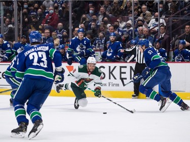 Minnesota Wild's Jordan Greenway (18) is checked to the ice in front of Vancouver Canucks' Tyler Myers (57) during the first period of an NHL hockey game in Vancouver, on Tuesday, October 26, 2021.