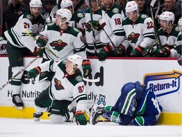 Vancouver Canucks' Kyle Burroughs, right, is hit by Minnesota Wild's Kirill Kaprizov (97), of Russia, during the third period of an NHL hockey game in Vancouver, on Tuesday, October 26, 2021.