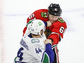 Vancouver Canucks defenceman Kyle Burroughs (44) fights with Chicago Blackhawks defenxeman Riley Stillman (61) during the first period at United Center.
