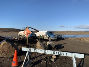 Trucks work by the Sylvia Grinnell River near Iqaluit, Nunavut on Wednesday, Oct. 13, 2021 after potential petroleum was discovered in the city's tap water, making it undrinkable.