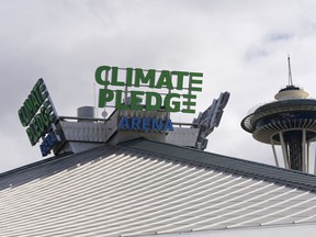 The roof-top sign for Climate Pledge Arena is shown next to the Space Needle, Wednesday, Oct. 20, 2021.