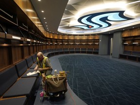 A worker puts the final touches on woodwork in the Seattle Kraken's locker-room at Climate Pledge Arena, Wednesday, Oct. 20, 2021, during a media tour ahead of the NHL hockey team's home opener Saturday against the Vancouver Canucks in Seattle. The historic angled roof of the former KeyArena was preserved, but everything else inside the venue, which will also host concerts and be the home of the WNBA Seattle Storm basketball team, is brand new.