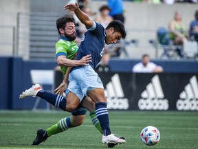 Vancouver Whitecaps midfielder Michael Baldisimo, right, and Seattle Sounders midfielder Joao Paulo, left, battle for possession in the first half of an MLS soccer match Saturday, June 26, 2021, in Seattle.