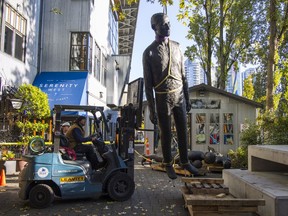 Jack Harman's The Family sculpture is lifted into place Friday morning at 1551 Johnston St. on Granville Island.