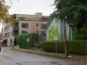 Photo showing a detached house in foreground, beside a multi-unit residential building, in Vancouver. The city is moving toward making it easier to build more of the four-storey units without complex zoning changes.