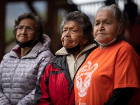 Kamloops Indian Residential School survivors and sisters, from left to right, Doreen Kenoras, 74, Sadie Kenoras, 79, and Camille Kenoras, 82, listen during a Tk’emlups te Secwepemc ceremony to honour residential school survivors and mark the first National Day for Truth and Reconciliation, in Kamloops on Thursday, September 30, 2021. The remains of 215 children were discovered buried near the former Kamloops Indian Residential School earlier this year.
