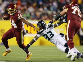 Antonio Gibson of the Washington Football Team carries the ball as Jamal Adams of the Seattle Seahawks defends during the fourth quarter at FedExField on November 29, 2021 in Landover, Maryland.