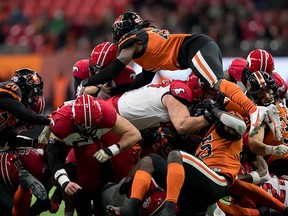 B.C. Lions' Jordan Williams, top right, leaps over the pile to try and stop Calgary Stampeders quarterback Jake Maier, back, as he carries the ball for a short yardage first down in the first half Friday.