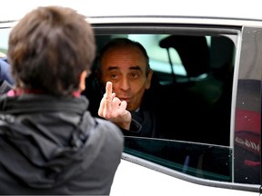 French far-right media pundit Eric Zemmour gestures towards a woman who insulted him as he leaves in his car after a visit in Marseille, southern France, on November 27, 2021.