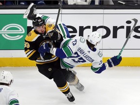 Boston Bruins' Brad Marchand (63) checks Vancouver Canucks' Oliver Ekman-Larsson (23) during the first period of an NHL hockey game, Sunday, Nov. 28, 2021, in Boston.